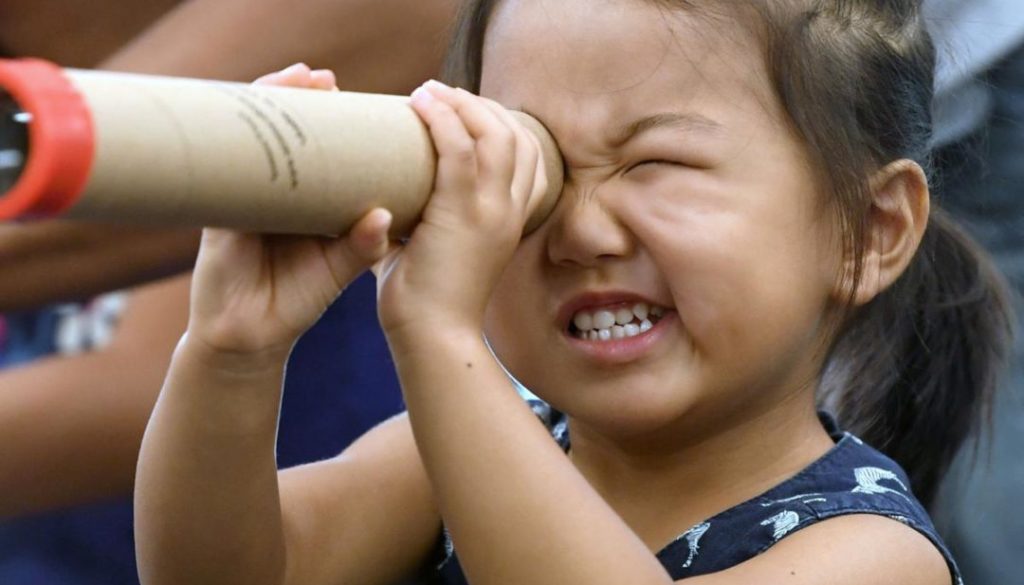Picture of little girl looking through a telescope